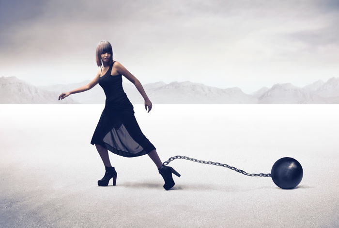 Woman dragging around a ball and chain representing why not letting go after divorce keeps you shackled to your negative emotions. Woman dragging around a ball and chain representing why not letting go after divorce keeps you shackled to your negative emotions.