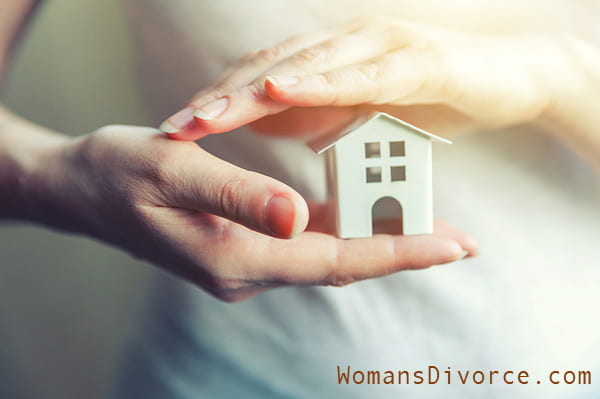 Woman with miniature house in hands signifying buying a house after divorce Woman with miniature house in hands signifying buying a house after divorce