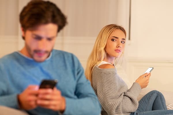Suspicious wife wonders Is he cheating? as she watches husband hiding a text suspicious woman watching man text