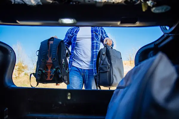 Man loading luggage in car for a trial separation Man loading luggage in car for a trial separation