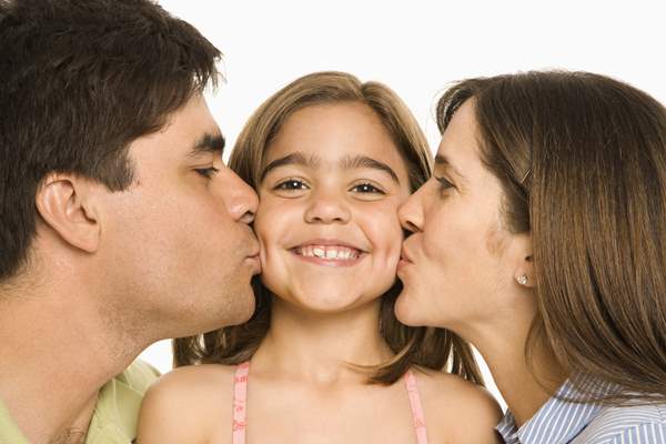 Young girl being kissed by both mom and dad. Young girl being kissed by both mom and dad.