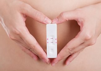 Woman holding positive pregancy test hoping a baby can save her marriage Woman holding a positive pregnancy test