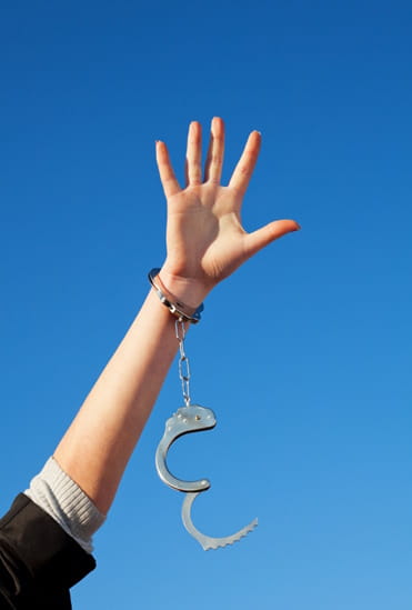 Woman's hand with opened handcuff reaching for the sky