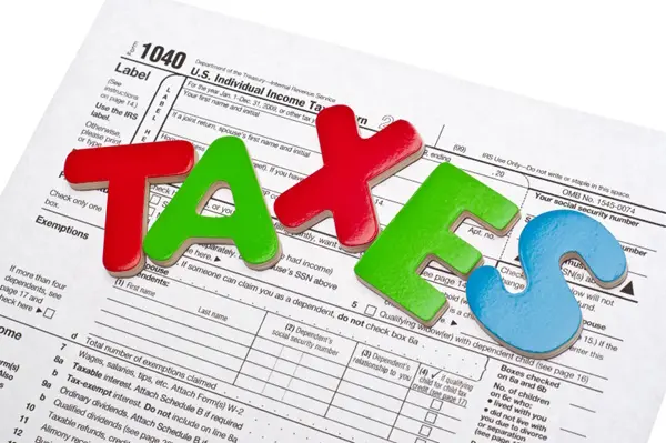Wood letters on tax form spelling out the word taxes letters on 1040 tax form spelling out taxes